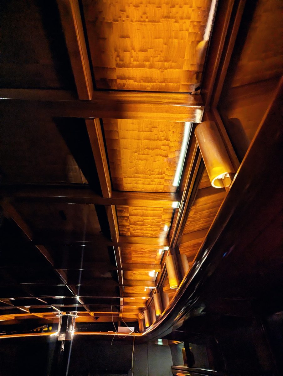 The mahogany deckhead above the saloon, lit warm by shaded lamps