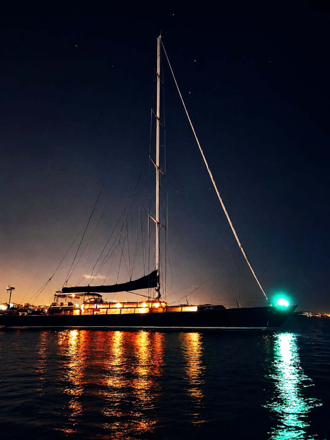 Lauren L lit at anchor after dark, her lights reflected across the water