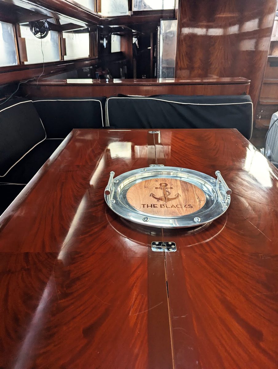 The mahogany dining table in the deckhouse, a polished anchor tray at its centre